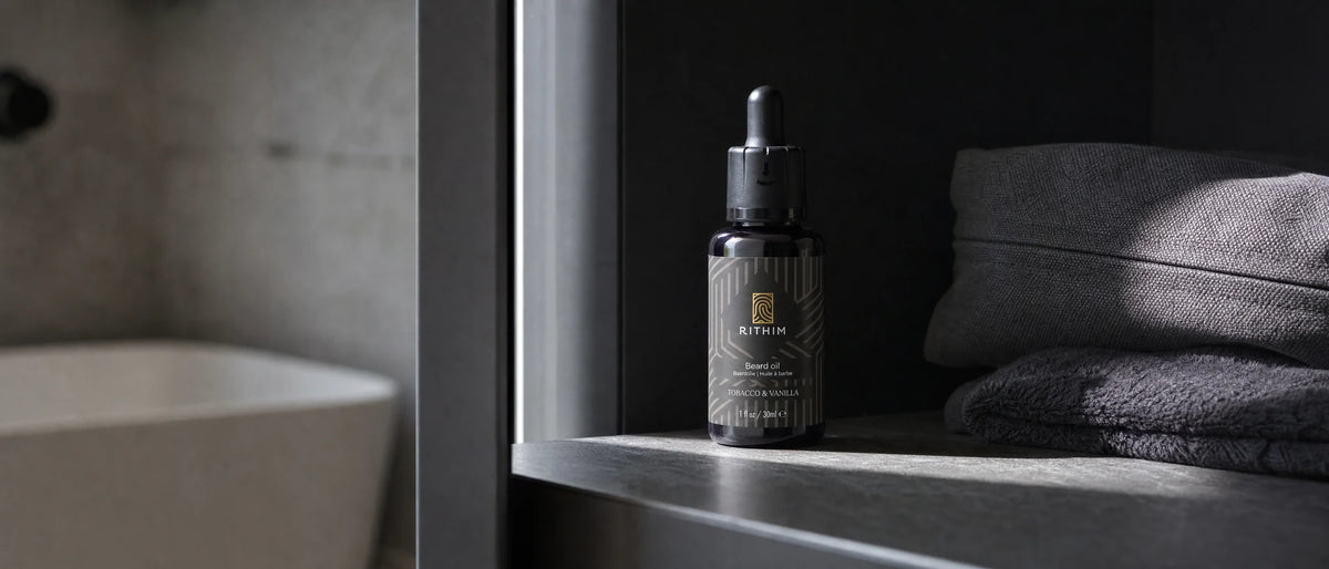 Flesje Tobacco & Vanilla baardolie in violet glas op een donkere plank in een badkamerkastje